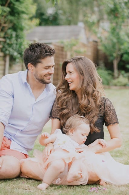 infleuncer couple looking at eachother whilst their baby begins to walk towards the camera