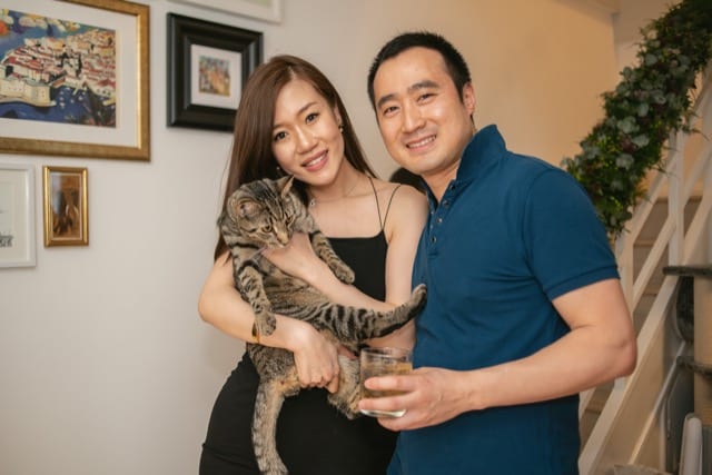 asian couple pose for a family photo at home with their cat
