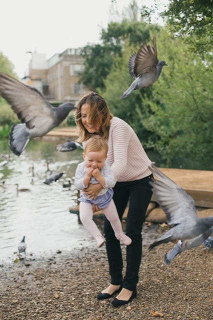woman holds young child as pigeons fly out of the photoshoot in the london park