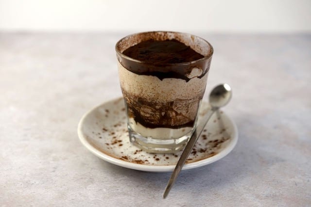 an espresso dessert, with a layer of cream, and topped with rich dark chocolate cocoa powder
