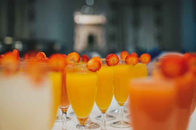 a table lined with chilled mimosas and tequila sunrises, in strawberry tipped glasses
