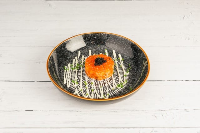 a sashimi fish cake with a japanese dressing below and topped with fresh beluga