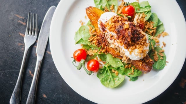 close up of poached egg on rye bread and topped with a crusted dressing