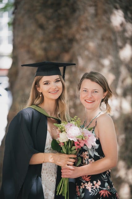 Two sisters pose for their bath graduation perfocal photoshoot with bouquet of flowers
