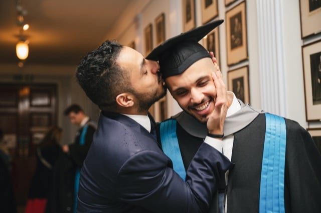 Friend kisses the head of his friend at his london university graduation photoshoot with Perfocal
