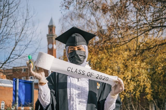 Girl with a mask, hand sanitiser and holding pieces of roll paper says 'Class of 2020' for her graduation photoshoot