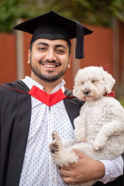 Boy in a graduation cap and gown holds his furry friend and celebrates with Perfocal graduation photoshoot