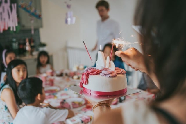 mother lighting up the candles on the cake for daughter's 4th birthday