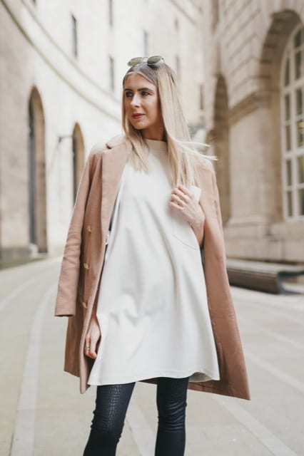 Blonde woman in a beige overcoat and cream top poses for her lifestyle photoshoot with Perfocal in London