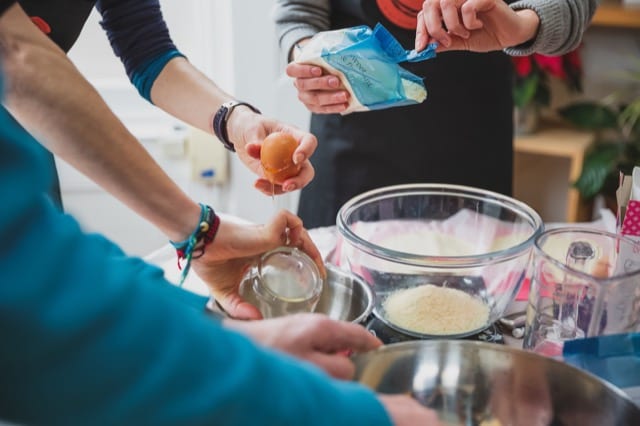 Close up of 3 people baking together with waitrose ingredients for their lifestyle photoshoot