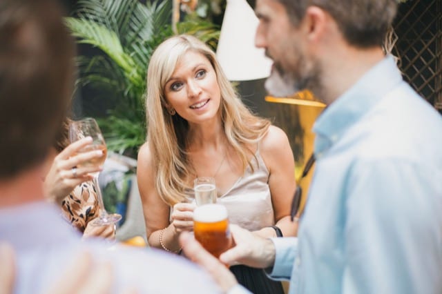 blonde woman celebrating a birthday with friends, with drinks in their hands