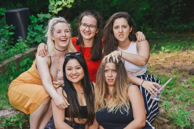 girls making funny faces for a group photograph on a outdoor party