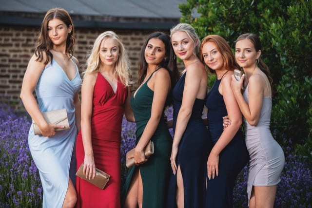 five young girls pose in their prom dresses before their party