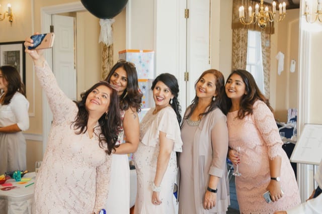 five asian women pose for a family selfie whilst having their photo taken.