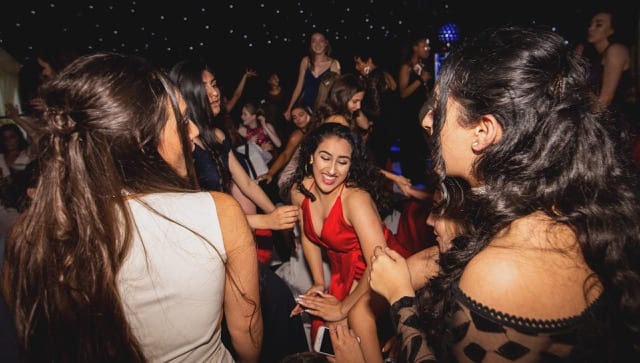 girl in red dress dancing in the crowd in a night club party