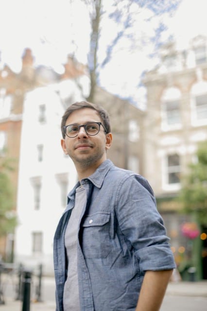 Man in casal blue shirt and glasses poses in london high street for his headshot