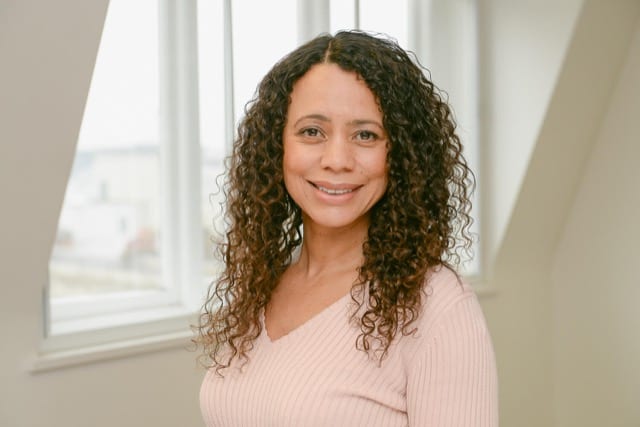 woman in a pink knitted jumper  poses for her portrait with a professional photographer