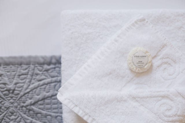 White folded towels on a bed topped with small, wrapped bars of hand soap