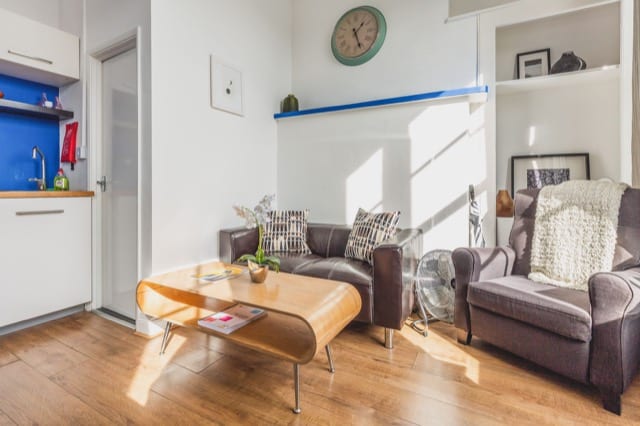 Wooden laminate floor with a small coffee table, and grey armchairs. In a small property in London