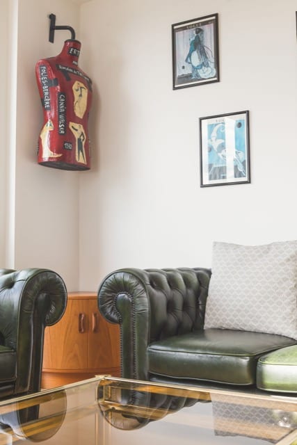 Two green leather sofas in a trendy living room, around a glass coffee table