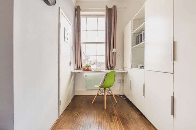 Photo of a study space in a studio flat. A green chair slotted underneath a minimalist desk