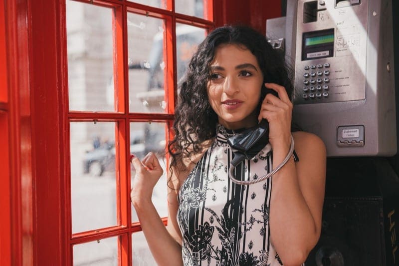 asian woman posing for travel photoshoot in red london telephone box