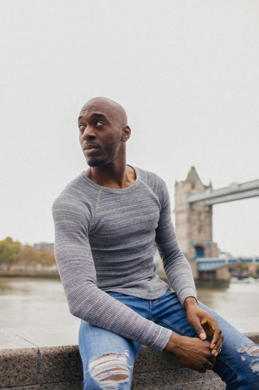 Man sits posing on wall in front of London Eye