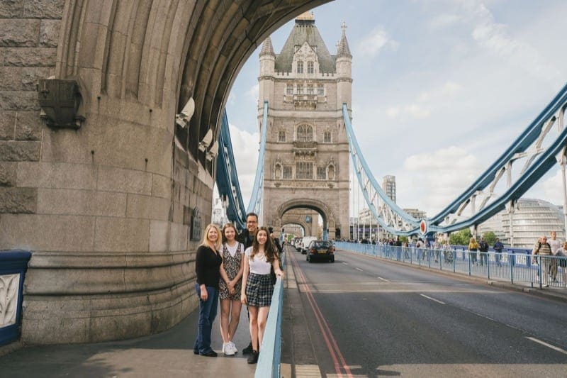 Family stand and smile for portrait in front of Tower Bridge in London