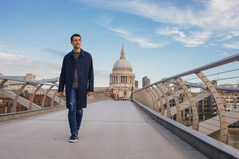 man walking along the millenium bridge, with st pauls in the background of his travel photoshoot