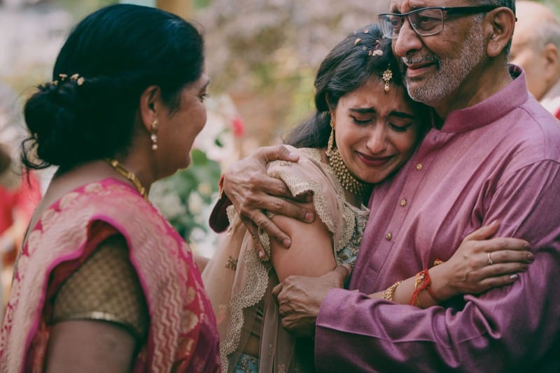 Indian bride hugs her father with joyful tears as her parents congratulate her on her wedding